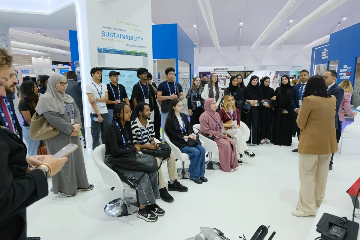 A group listening to a talk at a stand — ADIPEC 2025. Archive photograph.