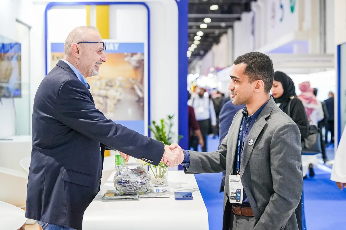 A handshake at an exhibition stand — ADIPEC 2025. Archive photograph.