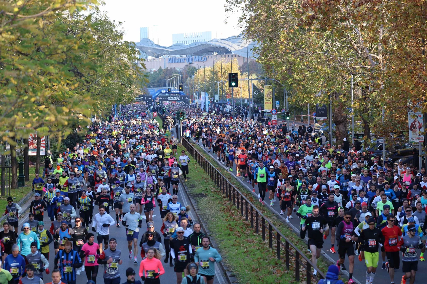 Runners fill both sides of a street, with Allianz MiCo visible in the distance.