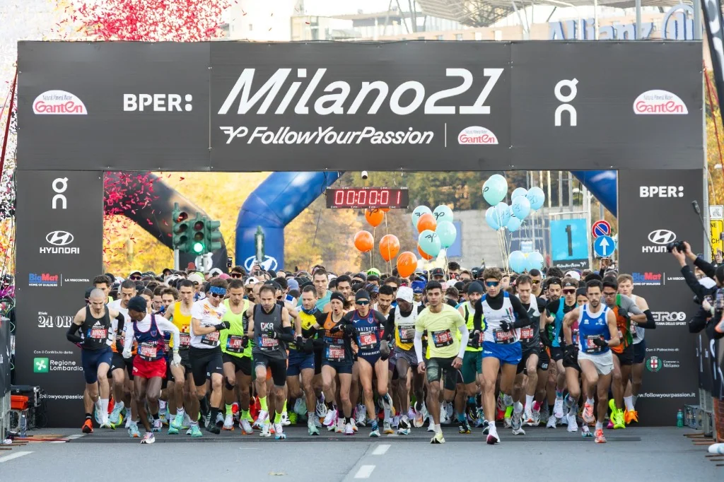 Die vorderen Läuferreihen unter einem schwarzen Milano21-Bogen mit Startuhr.