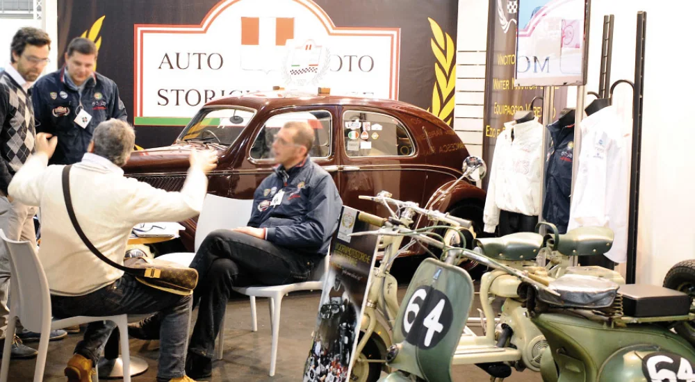 Uno stand di club con un’auto marrone e motociclette verdi.