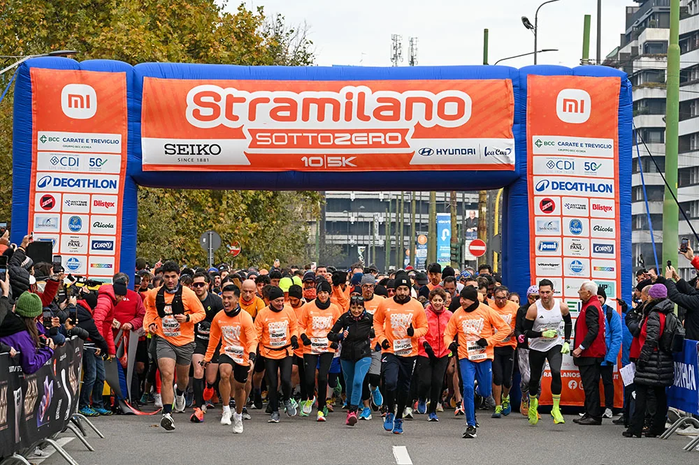 Runners in orange shirts set off beneath the Sottozero arch.