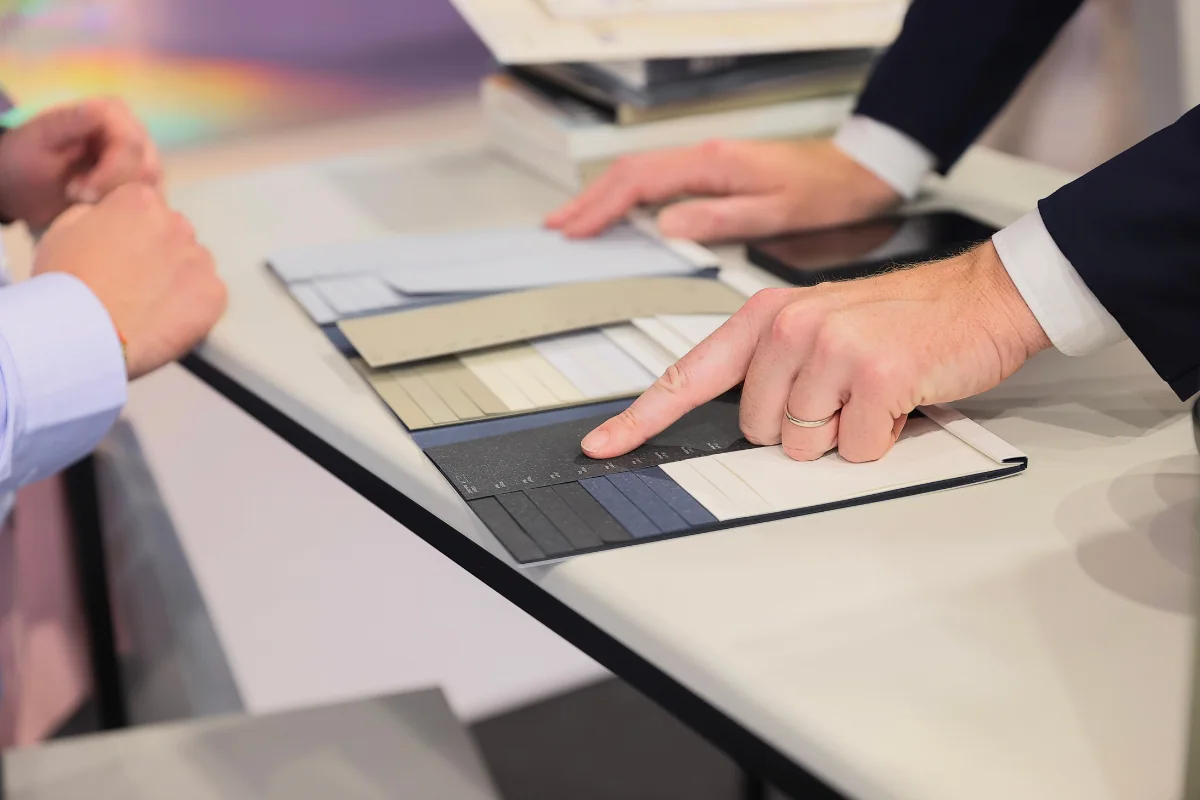 Visitors compare paper and board samples at a table.