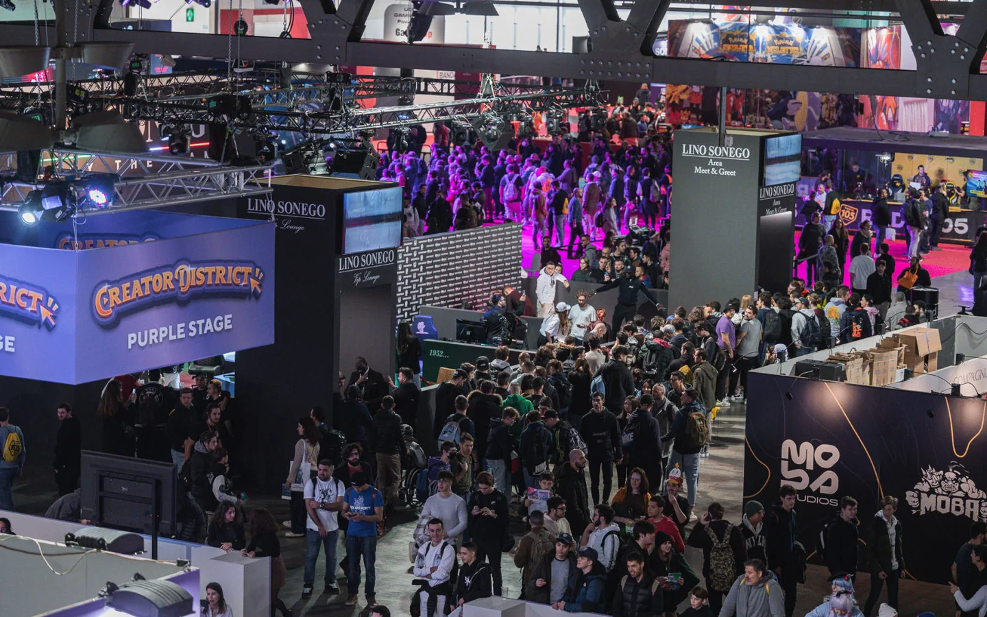 Visitors between stands and the Creator District Purple Stage area.