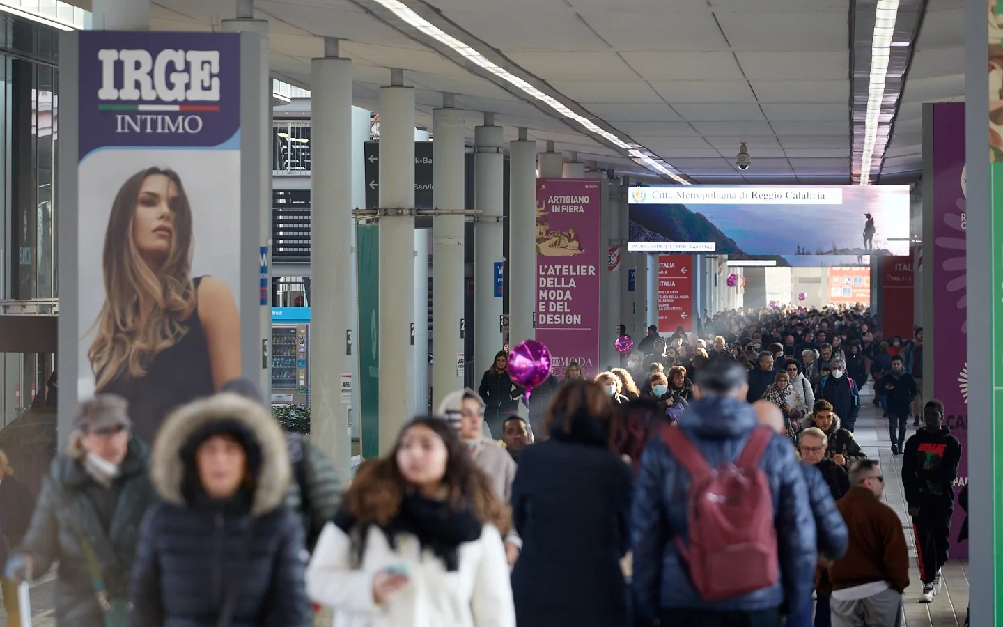 A busy aisle between stands beneath Artigiano in Fiera signs.