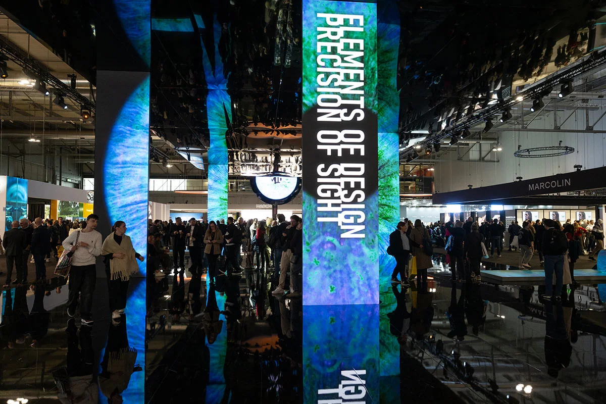 Visitors in an exhibition hall with mirrored illuminated columns.