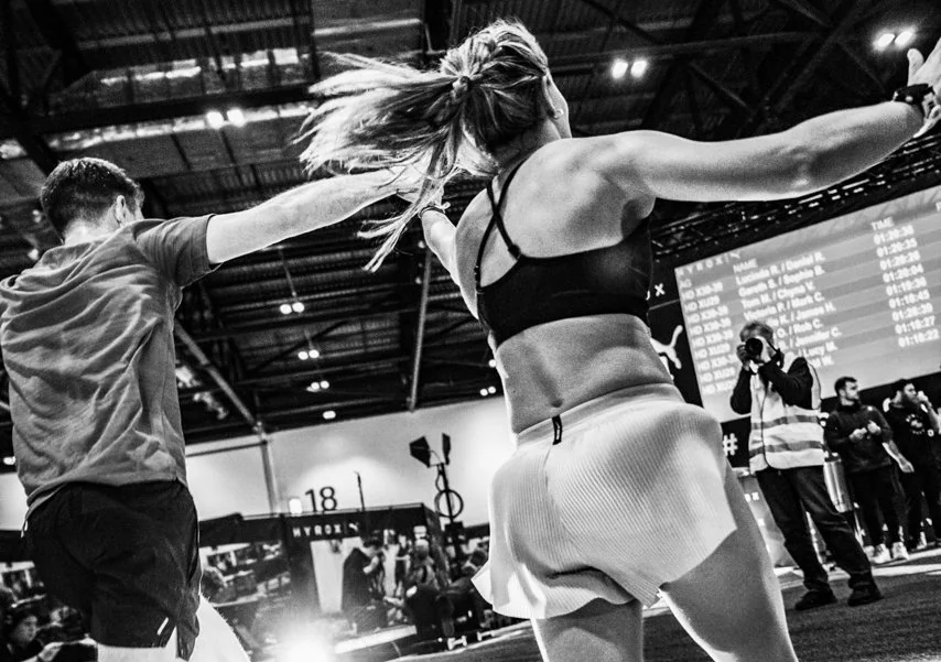 A man and a woman raise their arms inside a competition hall.