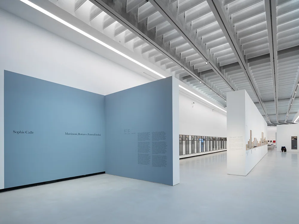 Secțiunea de intrare a expoziției Sophie Calle la MAXXI, cu panouri albastre și șiruri de lucrări.